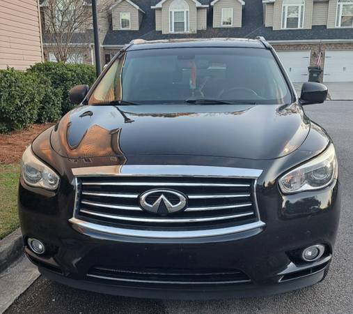 A black infiniti qx 6 0 parked in front of some houses.