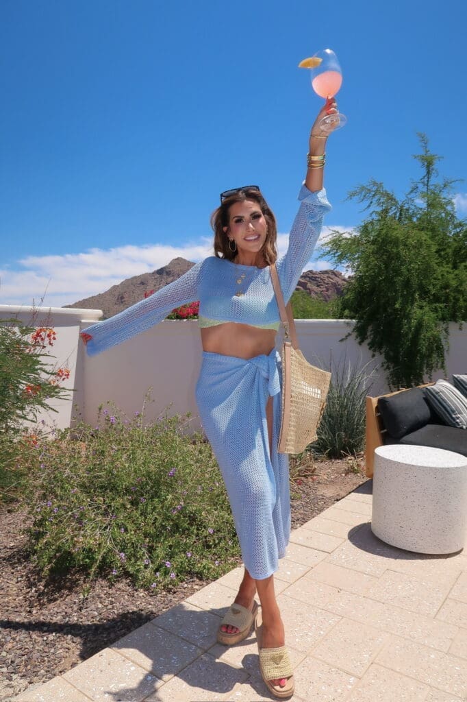 A woman in blue dress standing on top of a patio.