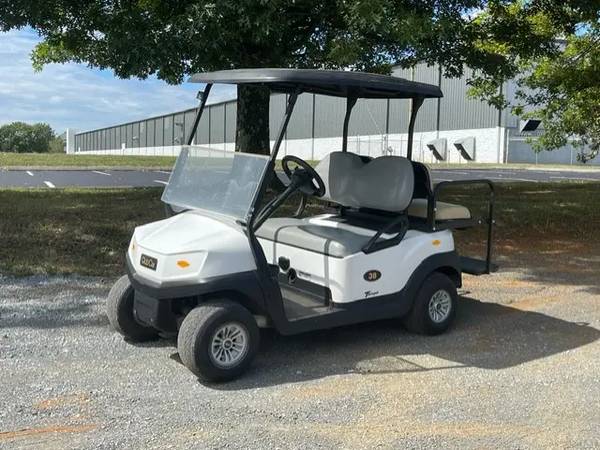 A white golf cart parked in the parking lot.