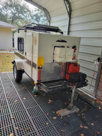 A small trailer with a door open on the ground.
