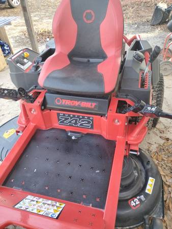 A red and black riding mower sitting on top of a field.