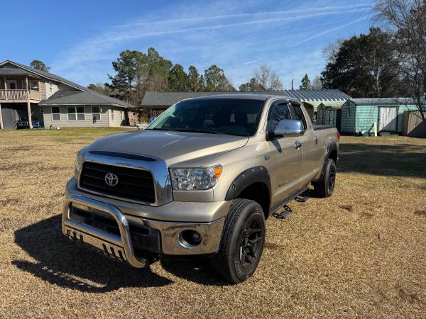 A silver truck parked in the grass near some houses.