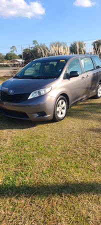 A gray van is parked in the grass.