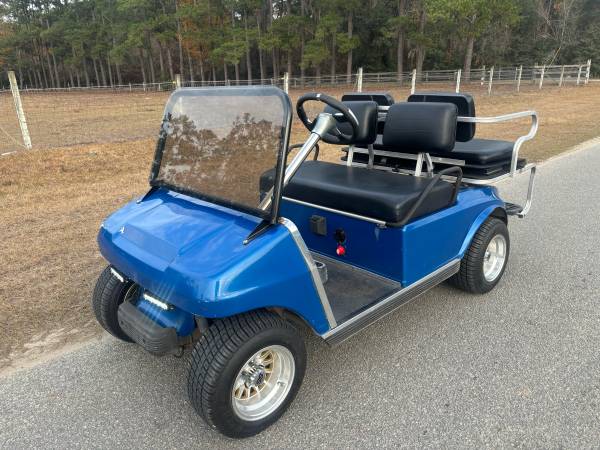 A blue golf cart with two seats and a windshield.