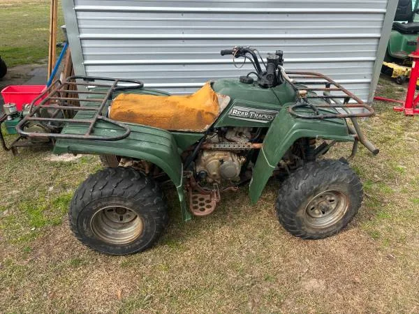 A green four wheeler parked in the grass.