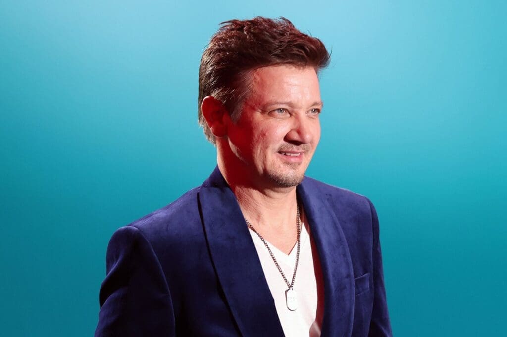 Jeremy Renner smiling against a blue background