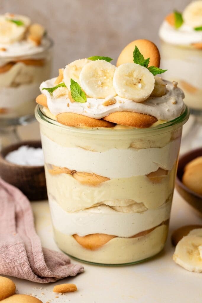 banana pudding in small glass jar with pink linen on the side