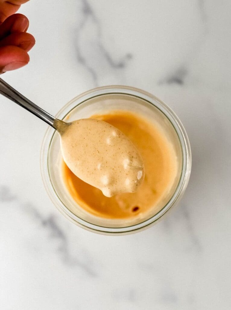 Overhead view of sauce in jar with spoon held over it.