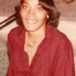Smiling person in a red shirt indoors.