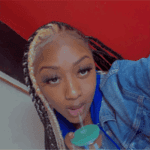 Woman sipping drink with braided hair.