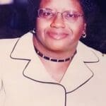 Smiling woman wearing glasses and a suit.