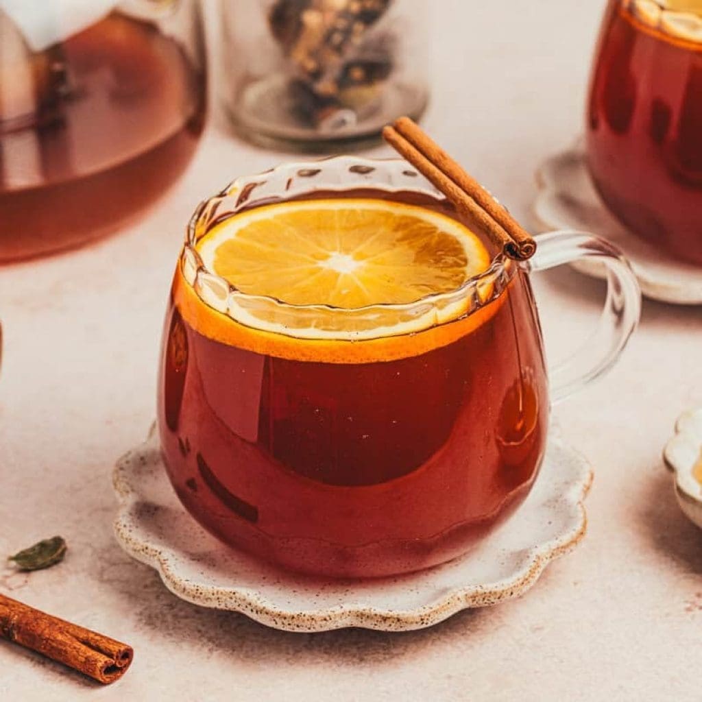 Chai Vanilla Bean Hot Toddy A glass of chai vanilla bean hot toddy with cinnamon sticks surrounding it.