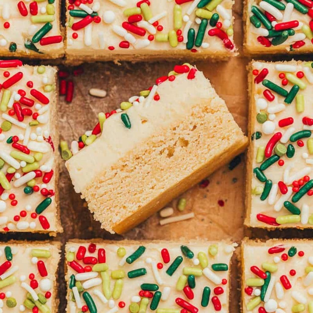 Frosted Sugar Cookie Night Clubs – A Timeless Spin Frosted sugar cookie bars sliced showing the top of the bar with sprinkles. One bar is flipped on its side showing the bar and the thick frosting.